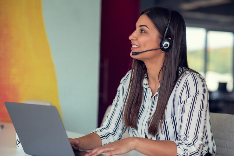 Young friendly operator woman agent with headsets working in a call centre.